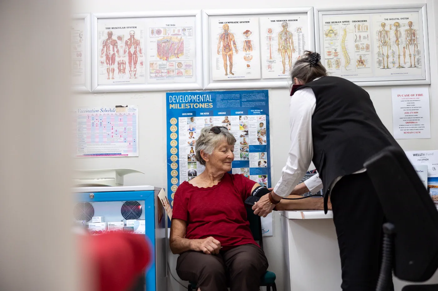 The clinic room at Albertyn Pharmacy, a nursing sister taking a seated patient's blood pressure beneath the wall charts
