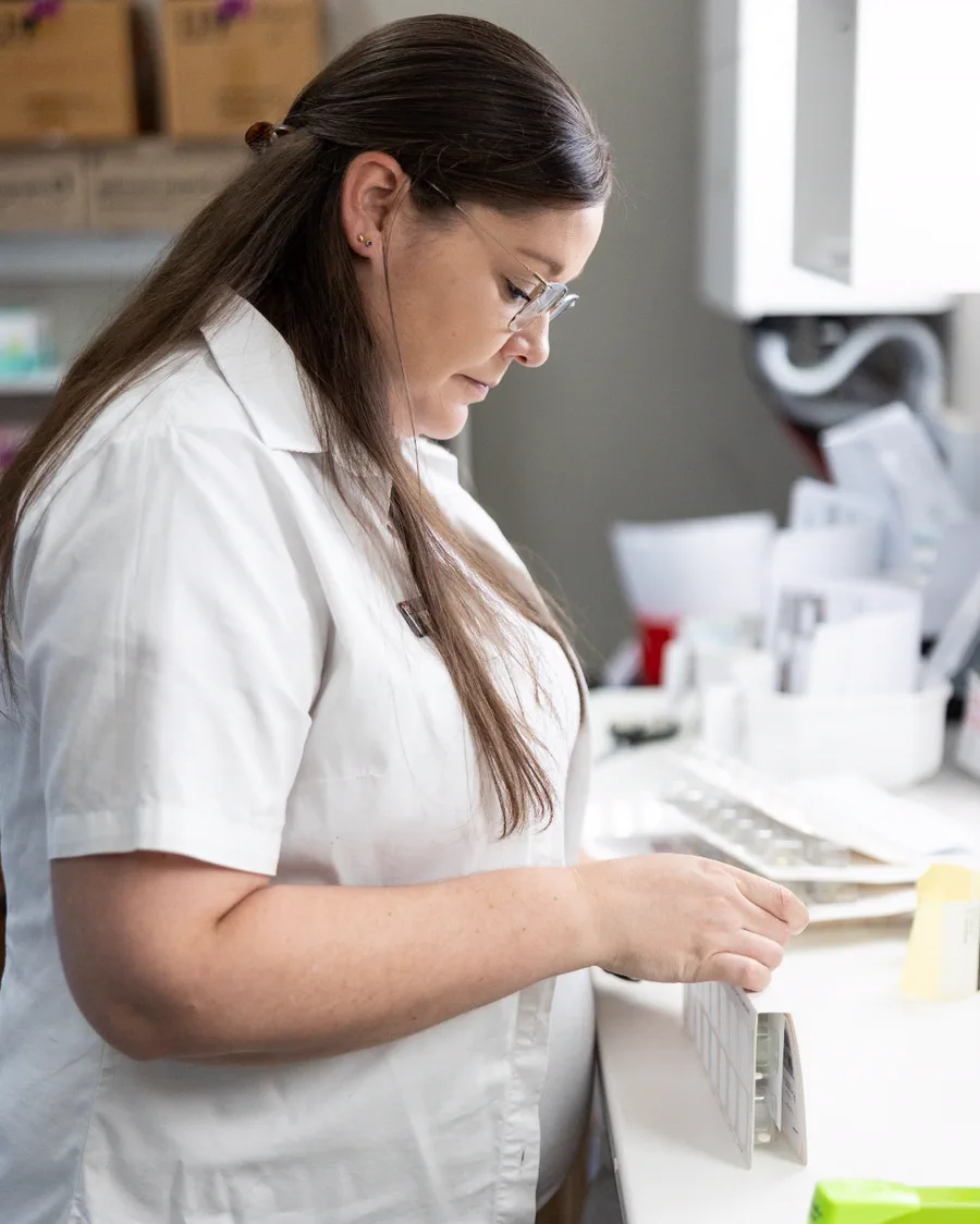 A member of the team pressing tablets into a dated blister pack in the back room