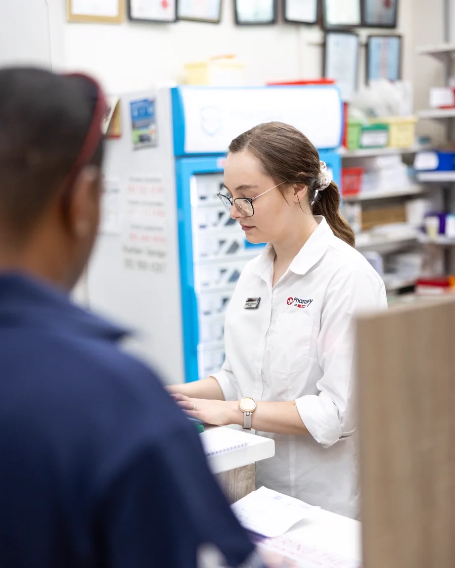 A pharmacist taking a prescription from a customer at the dispensary counter