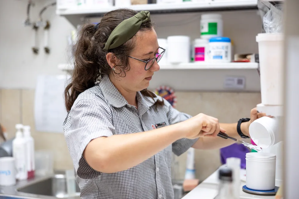 A pharmacy assistant weighing and measuring a preparation into a jar in the back room