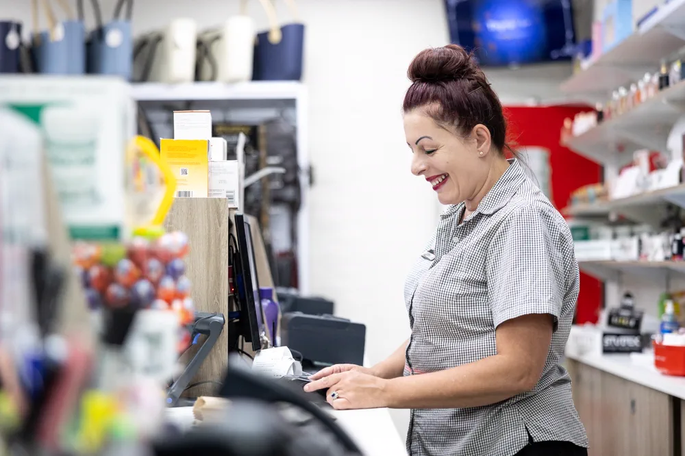 A member of the team ringing up a sale at the till in the front shop